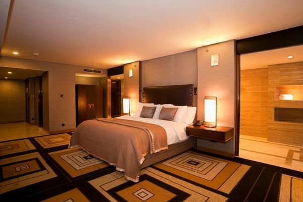 Custom upholstered bed with soft furnishings in hotel suite.